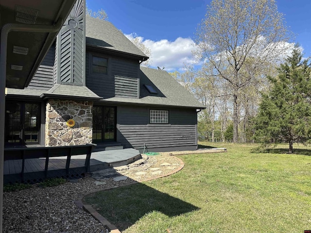 rear view of house with french doors, a shingled roof, stone siding, and a lawn