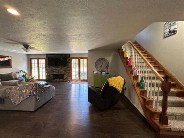 living area with a fireplace, plenty of natural light, a textured ceiling, and wood finished floors