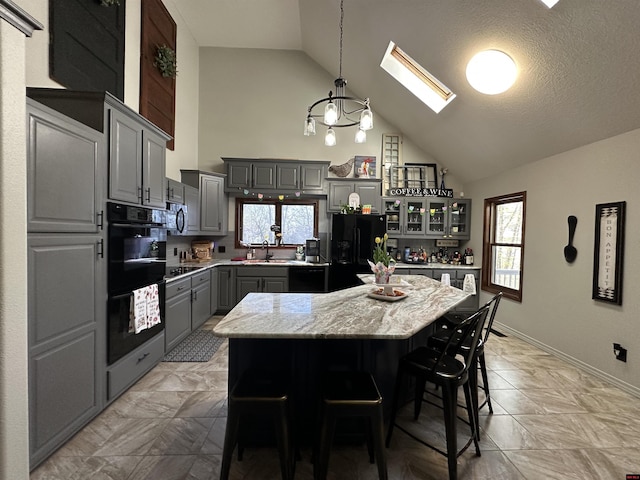 kitchen featuring high vaulted ceiling, a kitchen island, gray cabinets, a skylight, and black refrigerator with ice dispenser