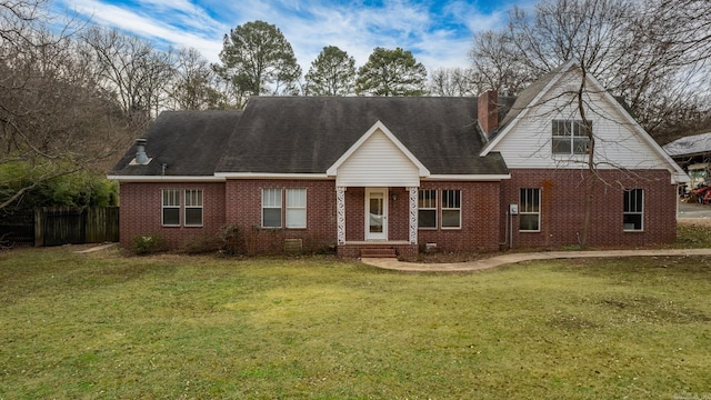 view of front of property featuring roof with shingles, brick siding, fence, and a front lawn