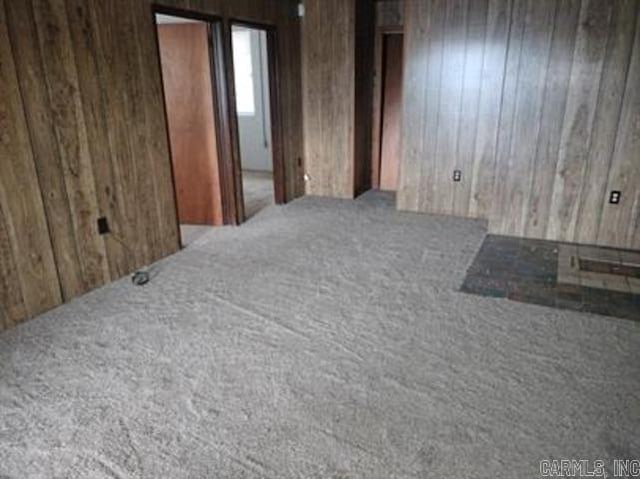 carpeted spare room with wooden walls