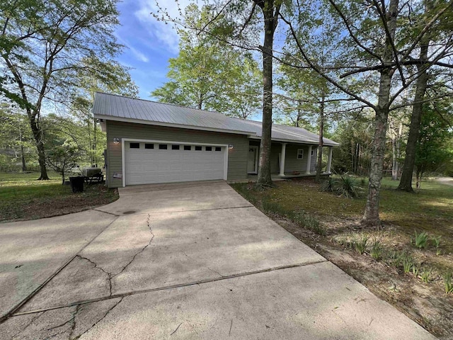 ranch-style house with metal roof, a garage, and driveway