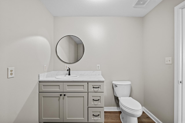 1216 Wade Ave, Judsonia, AR 72081 - half bathroom featuring vanity, baseboards, toilet, visible vents, and wood finished floors