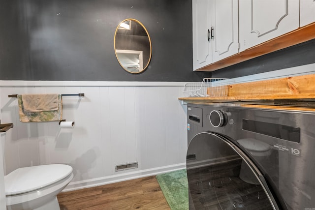 clothes washing area with laundry area, a wainscoted wall, wood finished floors, washer / dryer, and baseboards