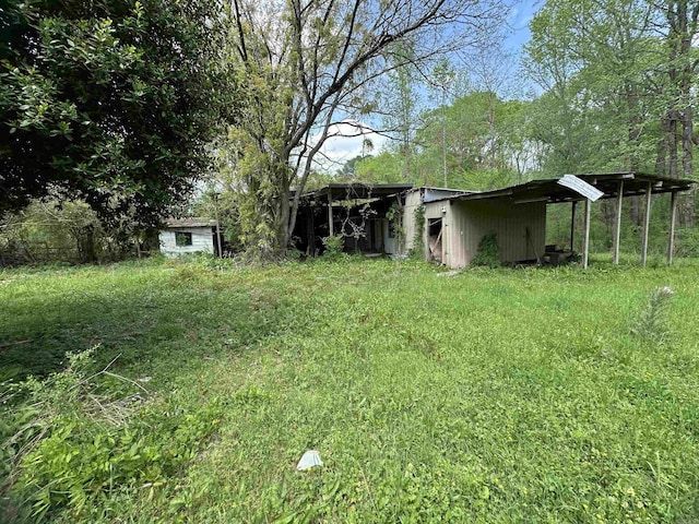 view of yard featuring a detached carport, a pole building, and an outdoor structure
