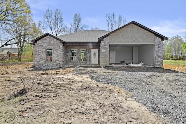 view of front of home featuring a carport, a shingled roof, and brick siding