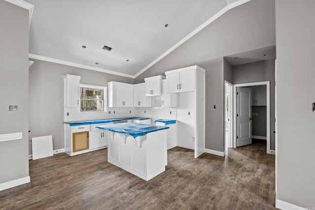 kitchen featuring ornamental molding, white cabinets, a kitchen island, dark wood-style flooring, and baseboards