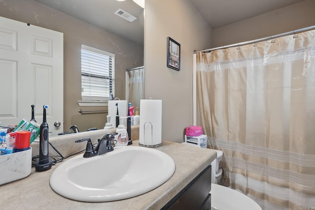 bathroom with toilet, vanity, a shower with shower curtain, and visible vents