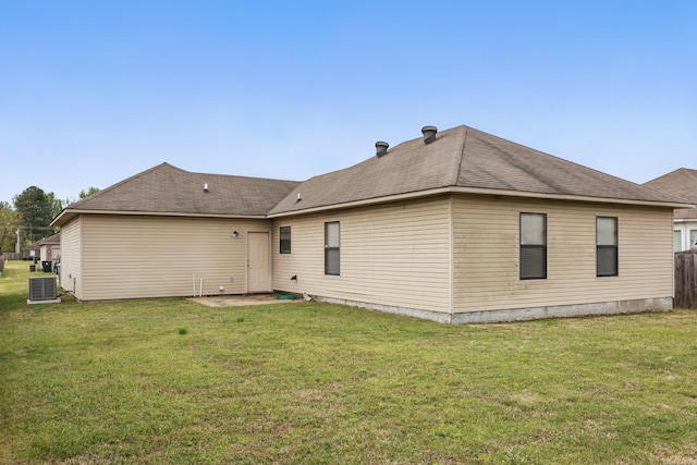 rear view of house featuring a lawn, cooling unit, and a shingled roof