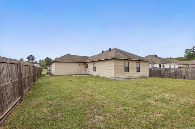 back of property with a lawn, central AC unit, and a fenced backyard