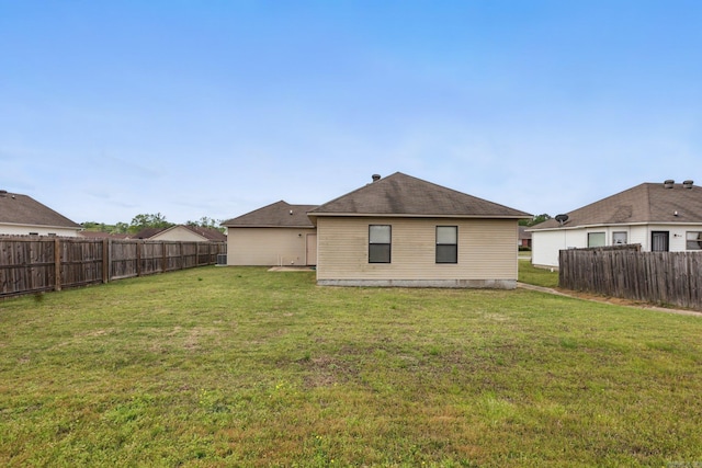 rear view of property with a fenced backyard and a lawn