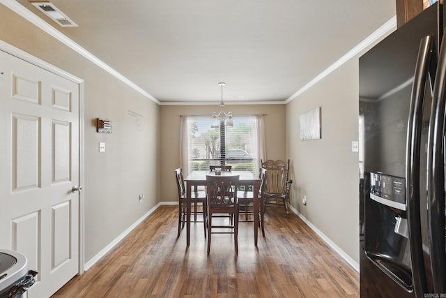 dining room featuring wood finished floors, ornamental molding, baseboards, a notable chandelier, and visible vents