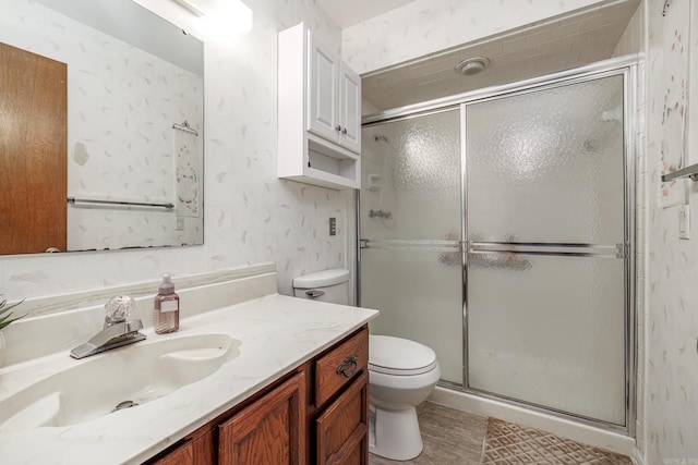 full bathroom featuring toilet, a shower stall, vanity, and wallpapered walls