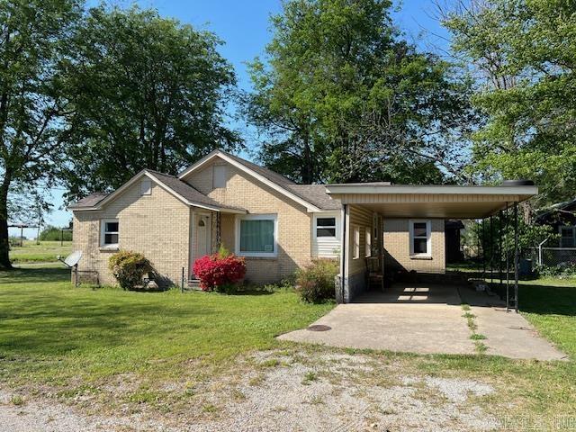 110 Ryerson St, Leachville, AR 72438 - view of front of house with a front yard, dirt driveway, brick siding, and a carport