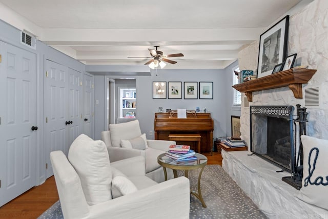5400 Southwood Rd, Little Rock, AR 72205 - living area featuring visible vents, a stone fireplace, ceiling fan, beam ceiling, and wood finished floors
