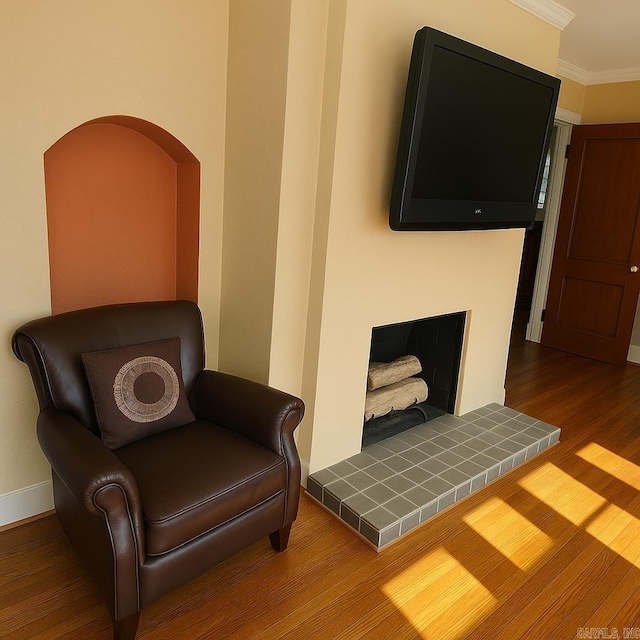 living area featuring baseboards, ornamental molding, and wood finished floors