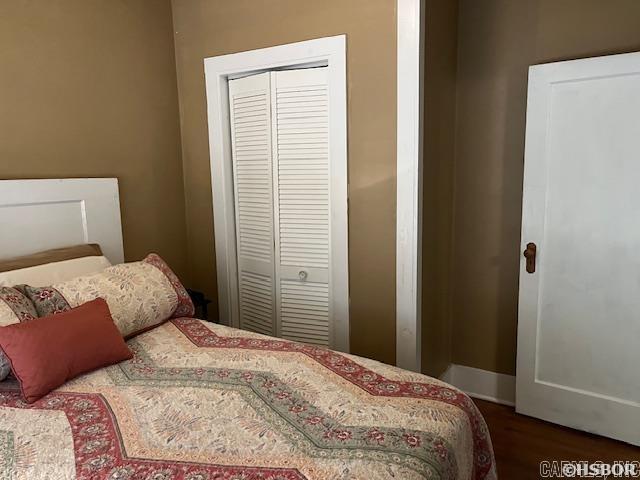 bedroom with a closet, baseboards, and wood finished floors