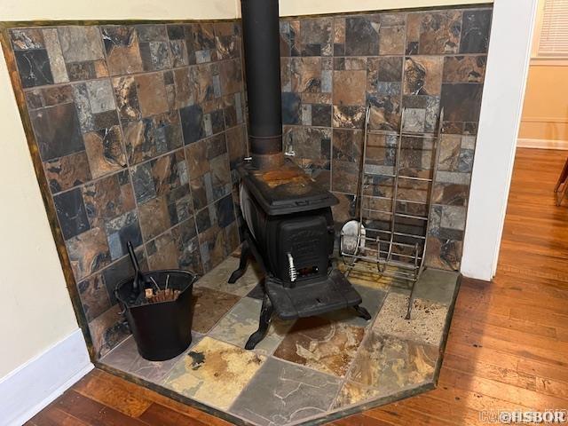 interior details featuring a wood stove, wood finished floors, and baseboards