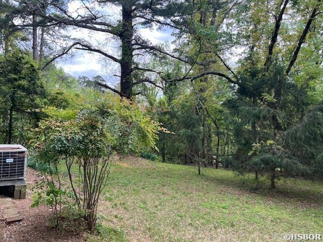 view of yard with a wooded view and central AC unit