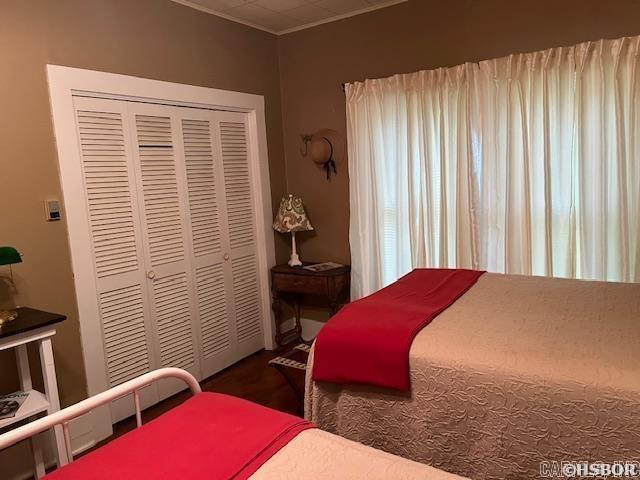 bedroom featuring crown molding, a closet, and wood finished floors