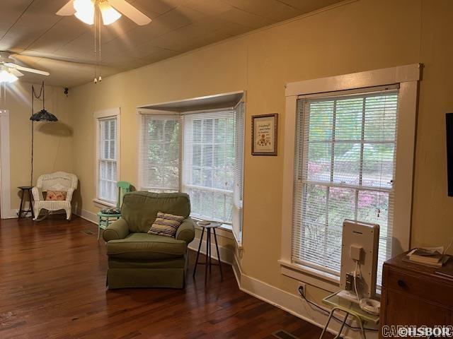 living area with baseboards, a ceiling fan, and wood finished floors
