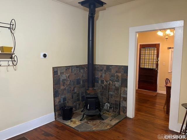room details with a wood stove, baseboards, and wood finished floors