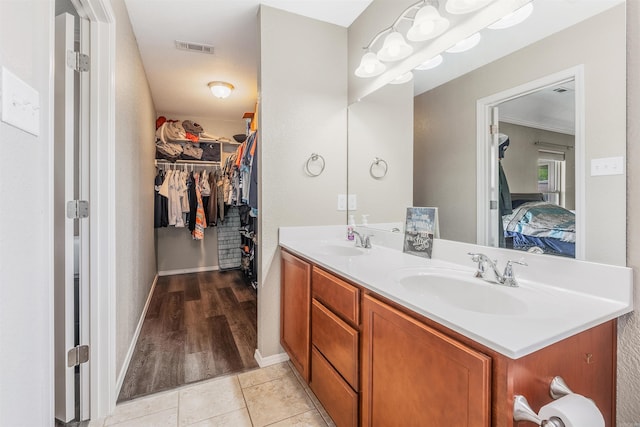 ensuite bathroom with a sink, visible vents, double vanity, and a walk in closet