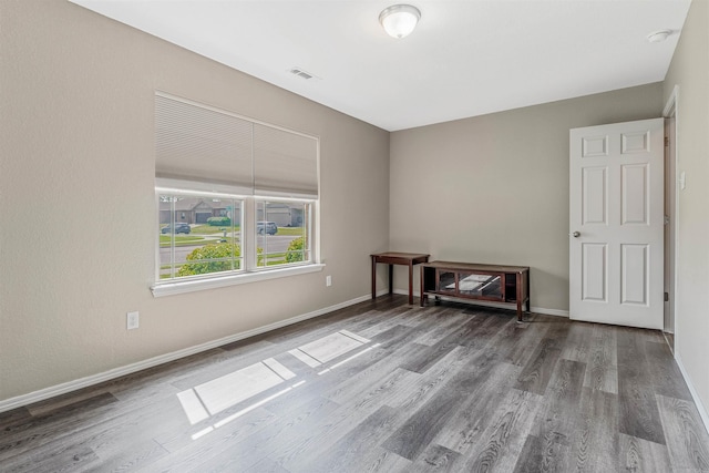 empty room with visible vents, baseboards, and wood finished floors