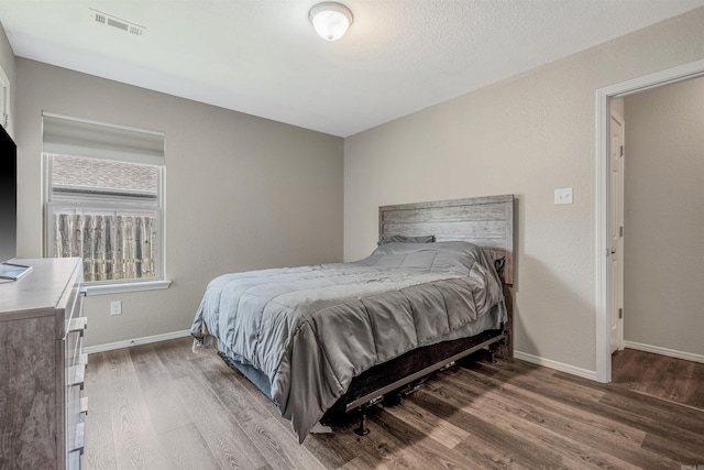 bedroom featuring visible vents, baseboards, and wood finished floors