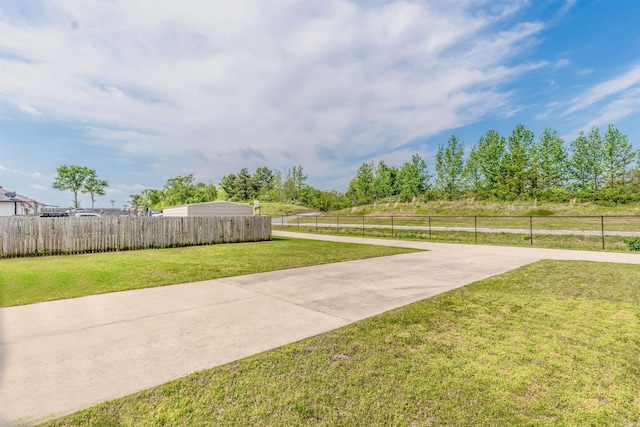view of yard featuring fence and concrete driveway