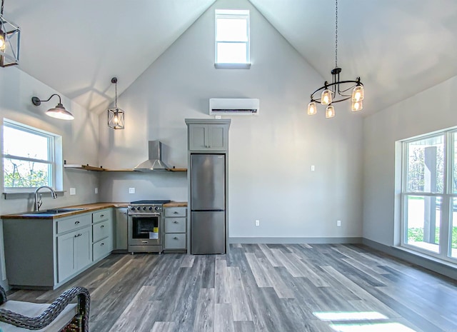 kitchen with a sink, wall chimney range hood, high vaulted ceiling, wooden counters, and appliances with stainless steel finishes