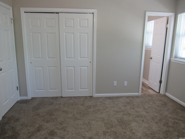 unfurnished bedroom with a closet, carpet flooring, and baseboards