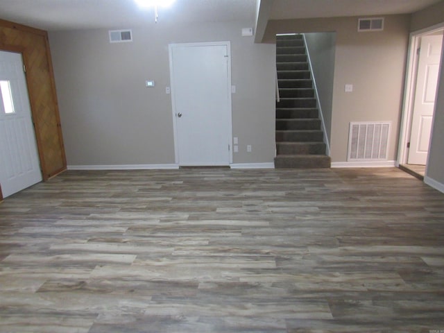 unfurnished living room with stairway, visible vents, and wood finished floors
