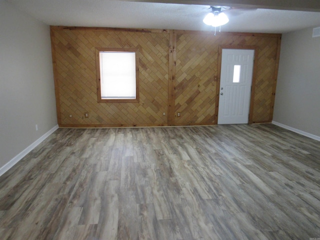 empty room featuring ceiling fan, wood finished floors, plenty of natural light, and baseboards