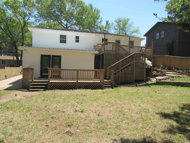 back of property with a wooden deck, fence, and a lawn