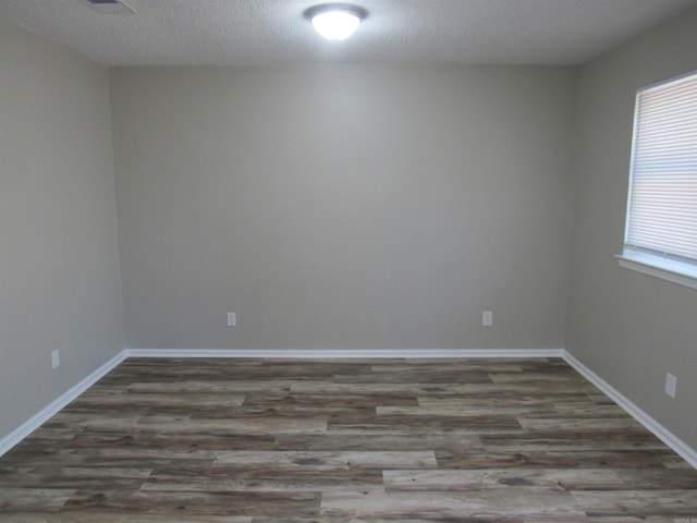 spare room with a textured ceiling, wood finished floors, and baseboards