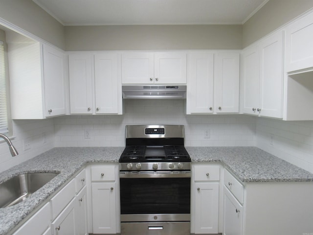kitchen featuring stainless steel gas stove, white cabinets, under cabinet range hood, a sink, and decorative backsplash
