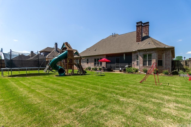 1130 Applewood Dr, Conway, AR 72034 - back of property featuring brick siding, a trampoline, a lawn, and a playground