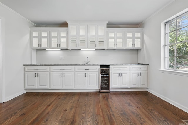 bar featuring indoor wet bar, baseboards, ornamental molding, beverage cooler, and a sink