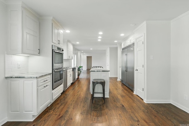 kitchen with white cabinetry, recessed lighting, light stone counters, dark wood-style flooring, and stainless steel appliances