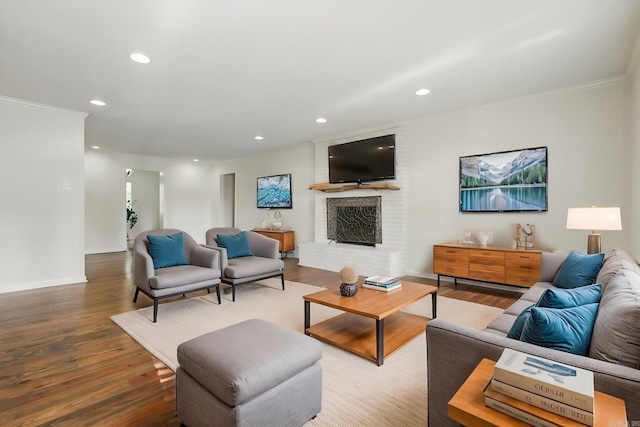 living room featuring crown molding, a brick fireplace, recessed lighting, and wood finished floors