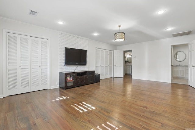 unfurnished living room featuring crown molding, wood finished floors, and visible vents