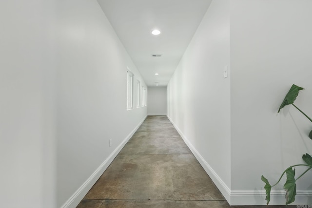 corridor with concrete flooring, visible vents, baseboards, and recessed lighting