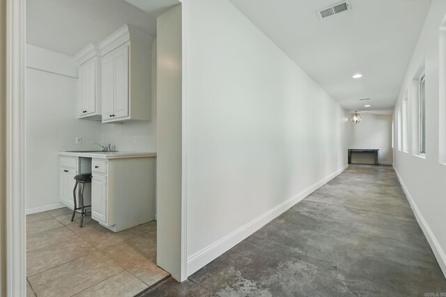 hallway featuring a sink, baseboards, visible vents, and recessed lighting