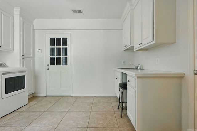 laundry area featuring visible vents, light tile patterned flooring, a sink, washer / dryer, and cabinet space