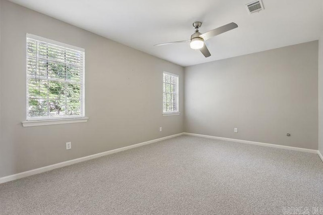 carpeted spare room featuring visible vents, baseboards, and ceiling fan