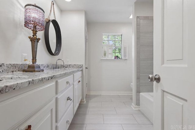 full bathroom with toilet, baseboards, vanity, and a bath