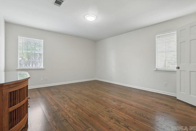 unfurnished room with visible vents, baseboards, and dark wood finished floors