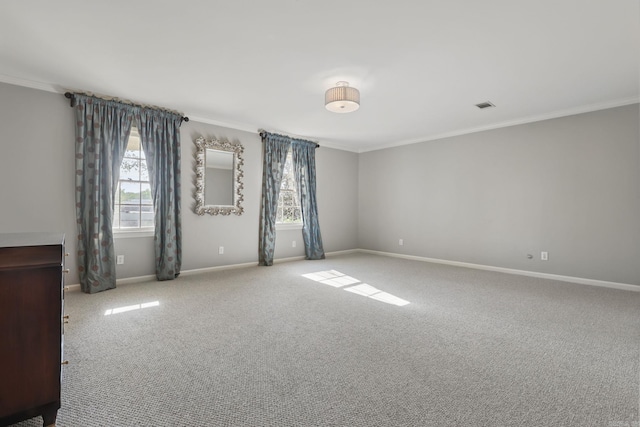 carpeted empty room featuring crown molding, visible vents, and baseboards
