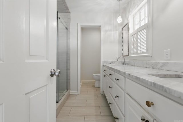 full bath with toilet, vanity, a stall shower, and baseboards